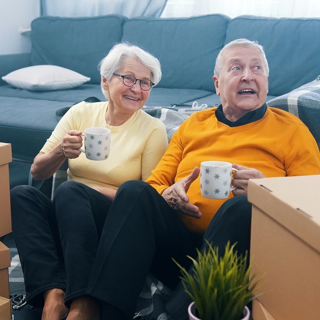 Aged couple happy to be relocating - surrounded by boxes